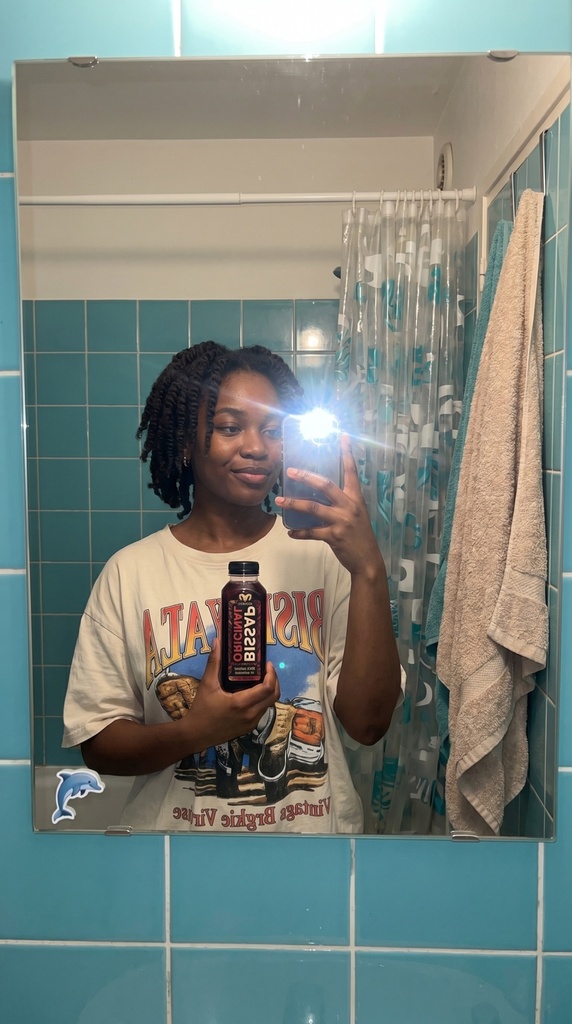 Selfie miroir salle de bain banlieue Paris jeune femme afro bouteille bissap